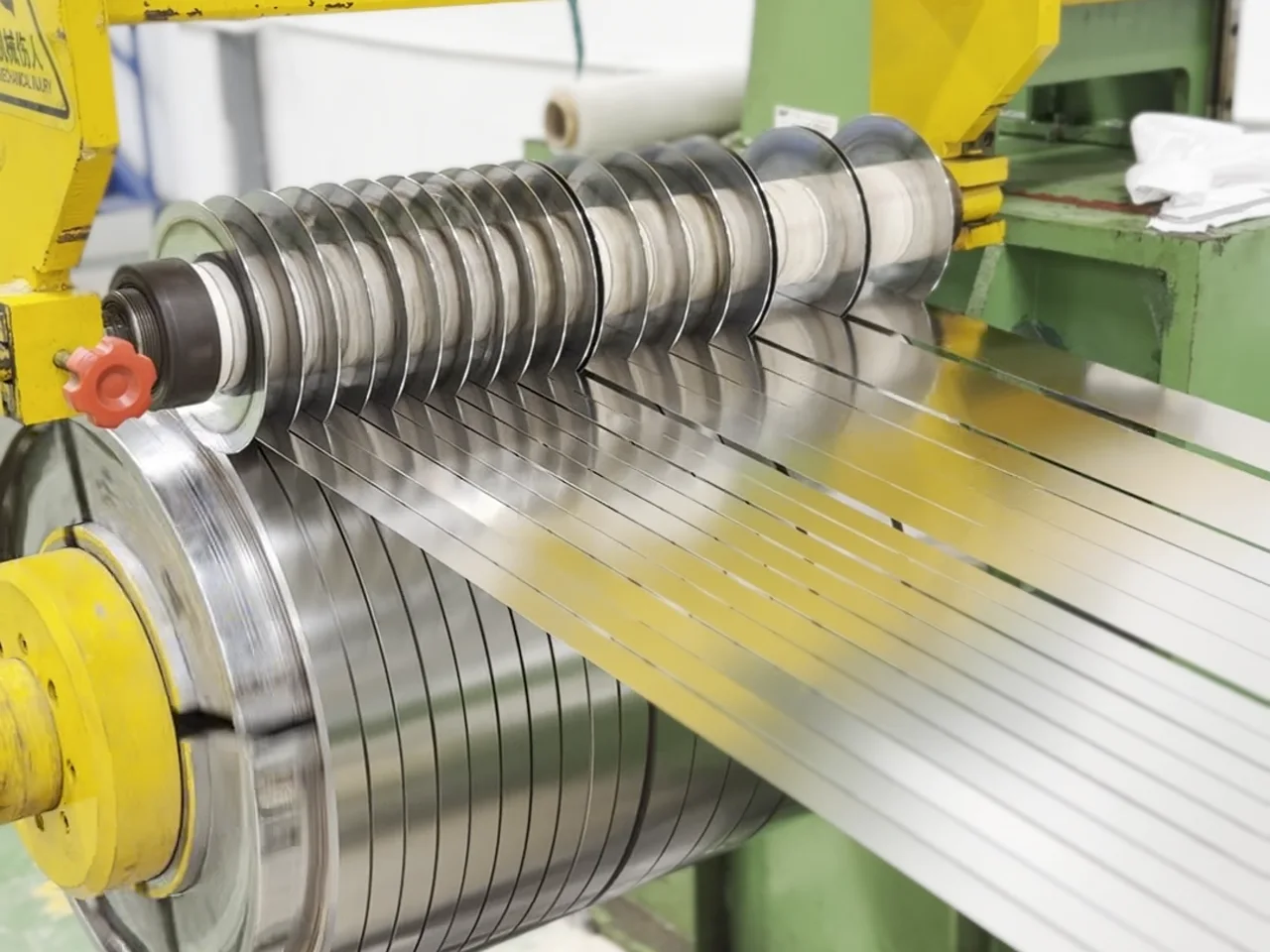 Strip logam keluar dari mesin slitting sesuai spesifikasi